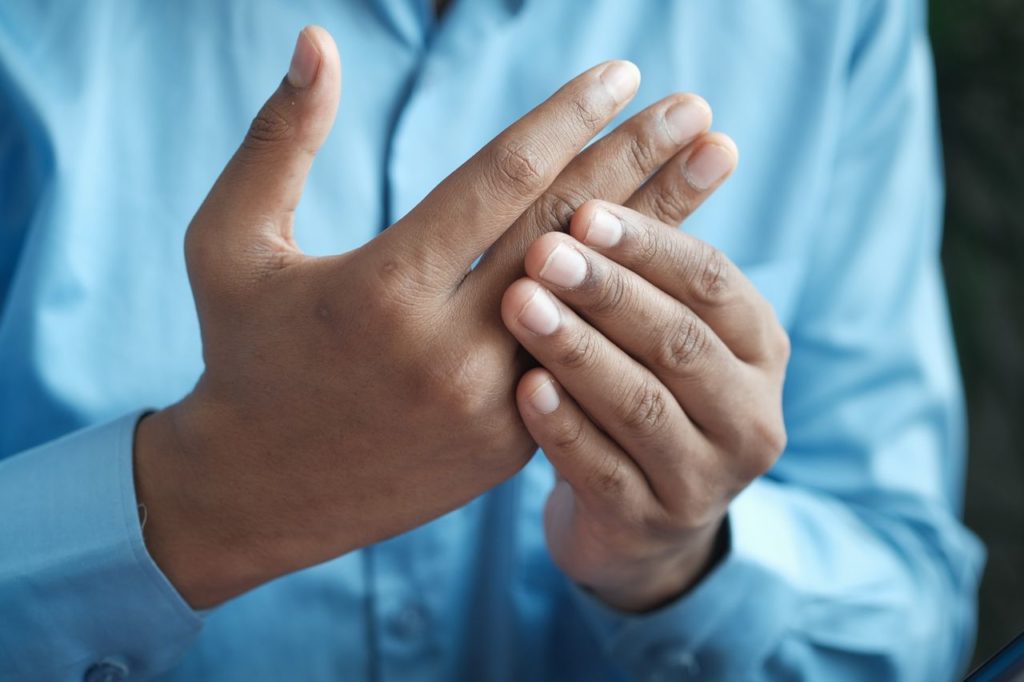 Someone holding their fingers due to painful inflammation. 