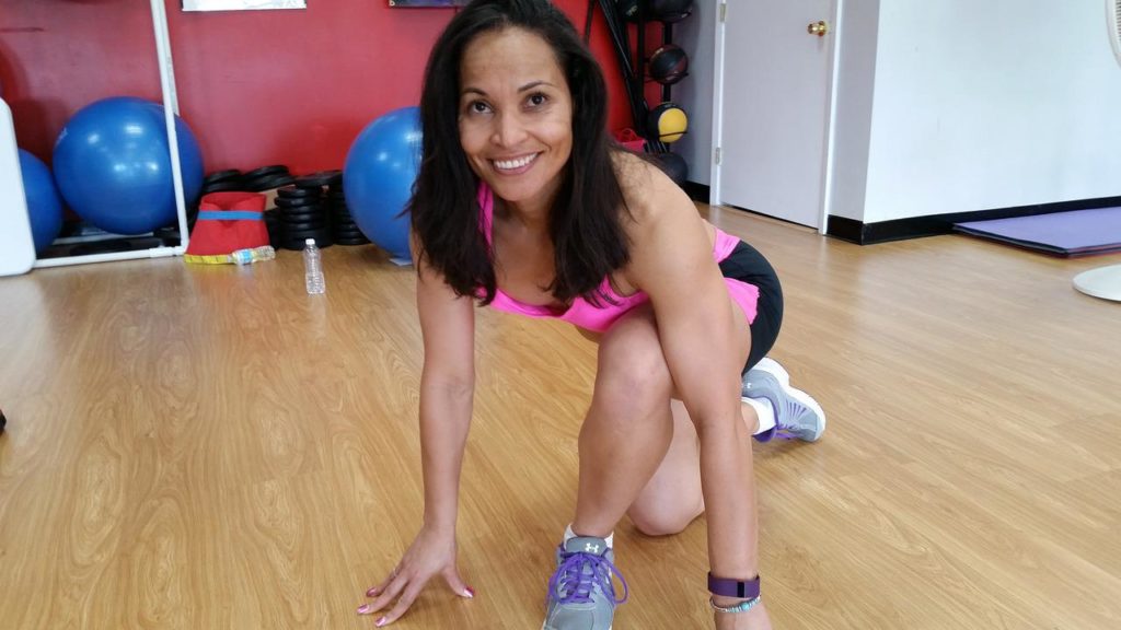 woman with dark hair kneeling on a gym floor